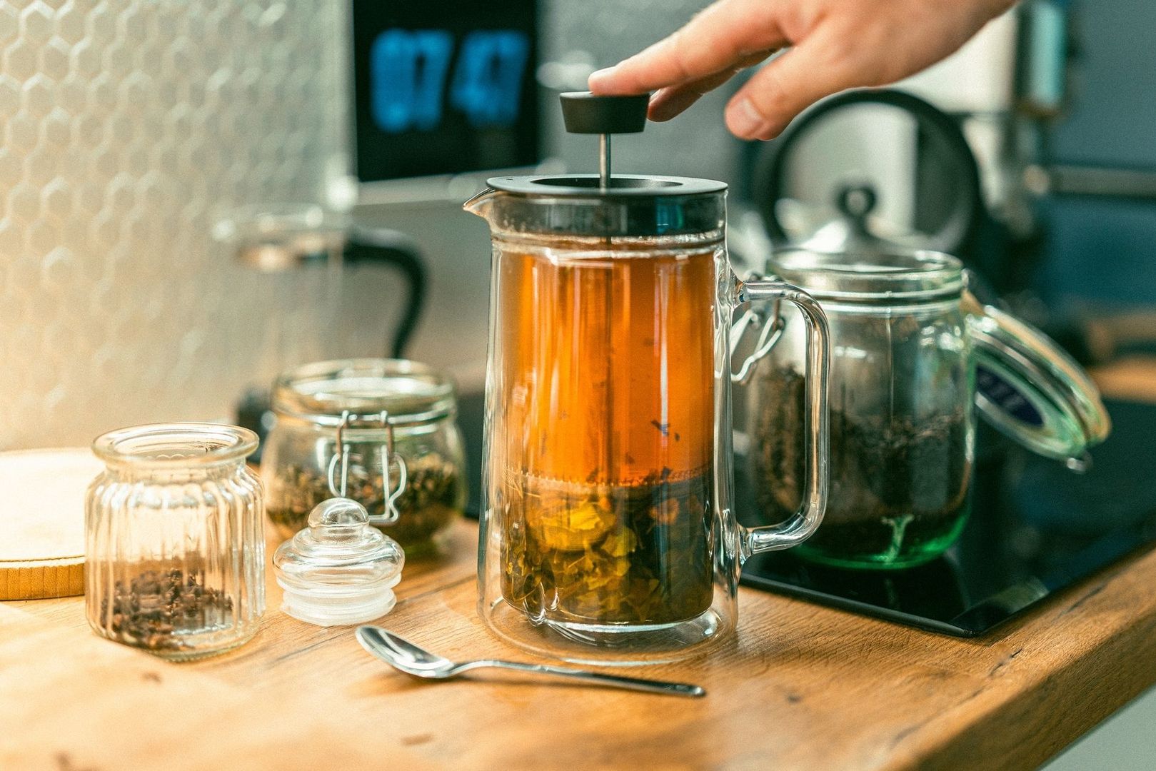 Hand pressar ner en sil i en glaskanna med varmt te